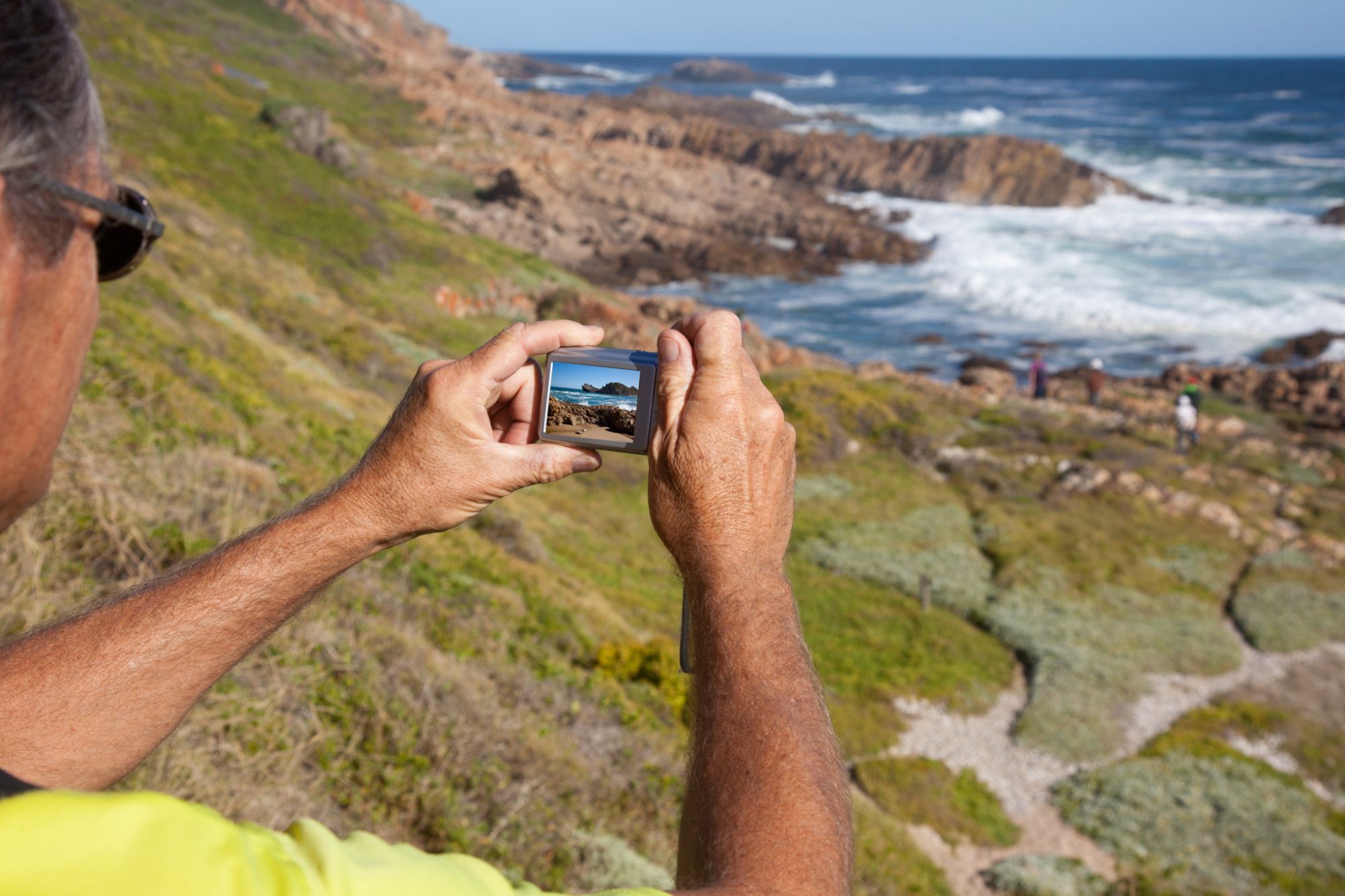 Picturesque image of person with a camera taking a picture of the ocean Picturesque image of person with a camera taking a picture of the ocean